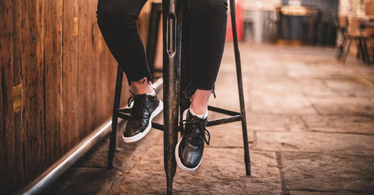 A pair of athletic Liberty slip-resistant style shoes being modelled in a restaurant setting