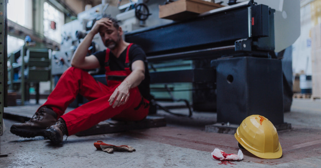 Industrial worker in pain after an injury in front of a workshop station