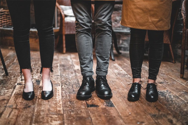 Three restaurant and bar staff members standing in the main room wearing three different chic and stylish shoes for working behind a bar