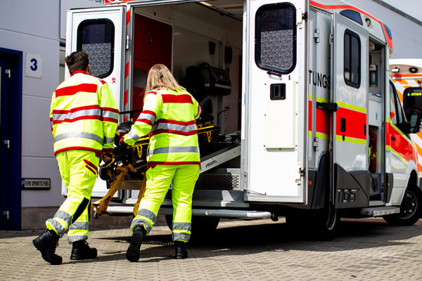 Two paramedics loading a stretcher into ambulance wearing supportive black Shoes For Crews work boots