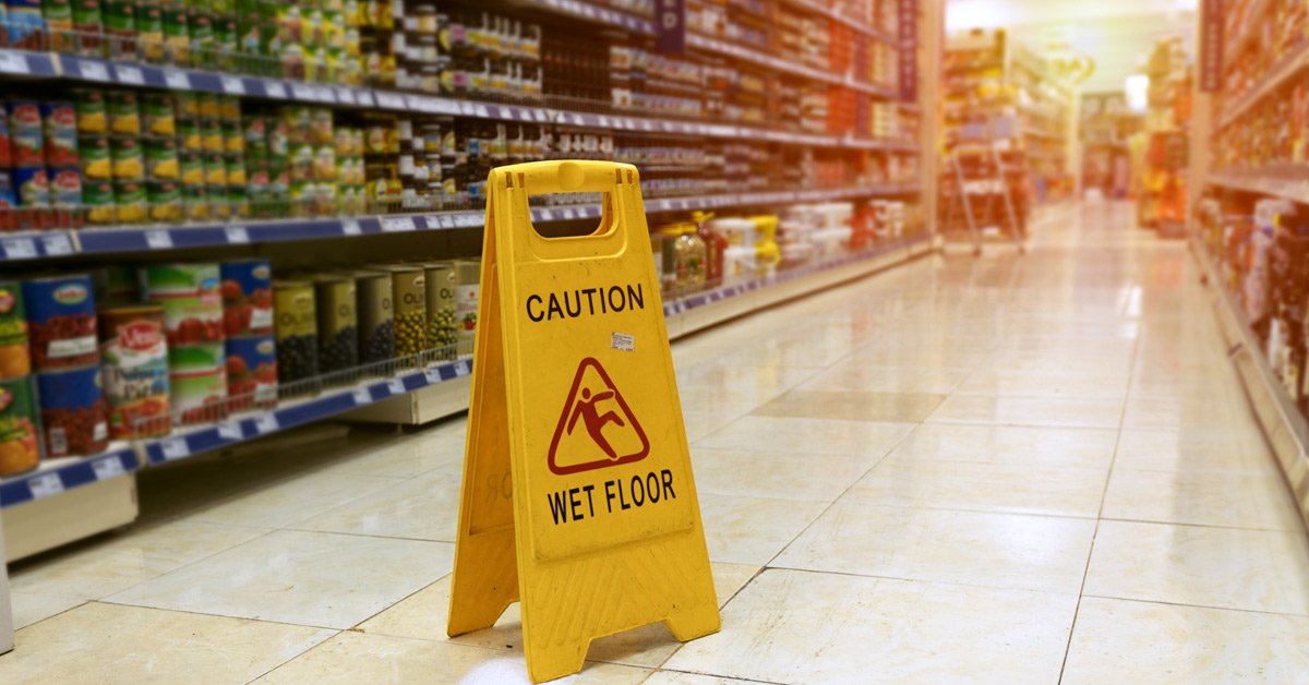 Yellow caution wet floor sign placed in the middle of supermarket aisle