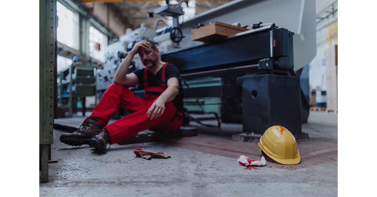 Industrial worker in pain after an injury in front of a workshop station